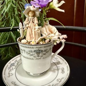 Shepherdess-Garden-Teacup Miniature garden in a teacup with a girl figurine, lamb, flowers, and matching saucer.
