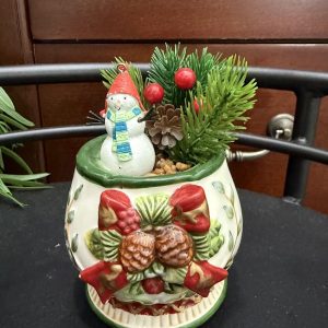 christmas-mug-snowman-winter-decor-pinecone-holiday A holiday-themed mug with pinecone and ribbon decorations holds a joyful snowman figurine, pine sprigs, berries, and mini pinecones.