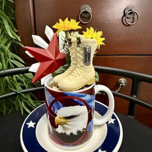 patriotic-army-military-mug-decor-boots-eagle-flower A patriotic mug with a bald eagle design is filled with miniature army boots, yellow flowers, and a red star, creating a tribute to military service.