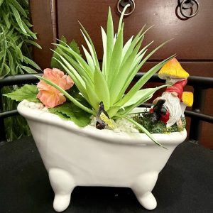 succulent-gnome-bathtub-fairy-garden-decor Whimsical bathtub-shaped planter filled with faux succulents, flowers, a gnome, butterfly, and miniature mushroom.